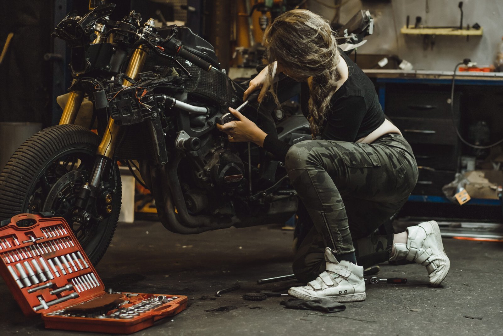 beautiful girl with long hair garage repairing motorcycle scaled